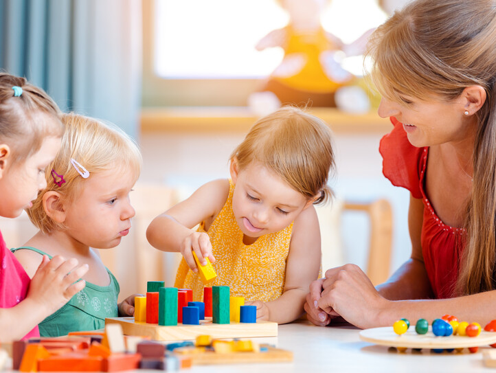 Group of children and teacher playing in kindergarten